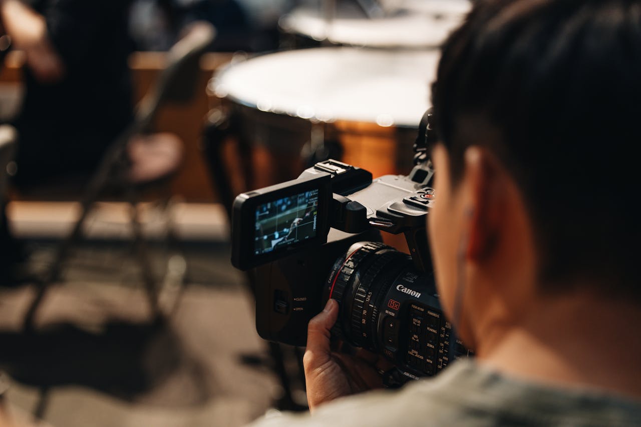 about-01 Filmmaker focuses intently as they capture video using a Canon camera in a studio setting.