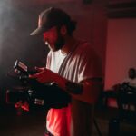 Professional cinematographer operating a camera indoors with dramatic lighting.